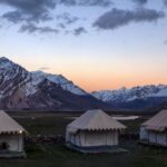 Beautiful tent camp at sunset with snowcapped Himalayan peaks in Zanskar Valley, Ladakh.