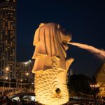 Vibrant night scene of the iconic Merlion statue in Singapore with cityscape.