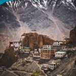 Picturesque Himalayan village beneath snow-capped mountains, showcasing unique architecture and natural beauty.
