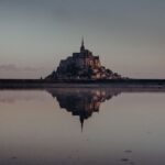 Enchanting view of Mont Saint-Michel reflecting in the water during twilight, Normandie, France.
